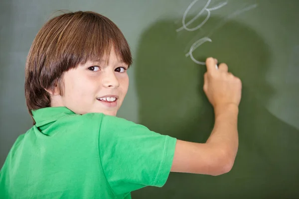 良い進歩を遂げた 学校の授業中に黒板に文字を書く男の子 — ストック写真