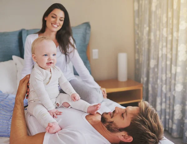 Stock image Happy mother, father and fun with baby in bedroom for love, care and quality time to relax together at home. Mom, dad and parents playing with infant kid for happiness, support or newborn development.