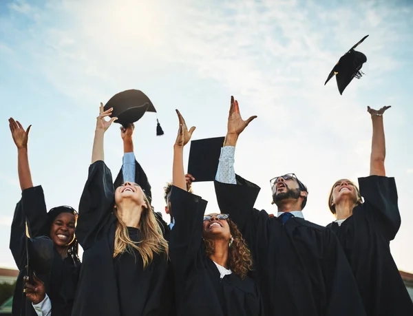 我们可以自由地实现我们的梦想 一群面带微笑的大学生在毕业典礼上欢呼着 把帽子扔在外面 — 图库照片