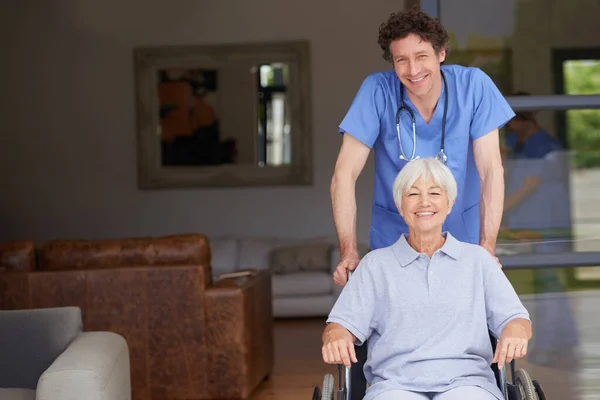 照顾好他的病人把老年病人推上轮椅的医生 — 图库照片