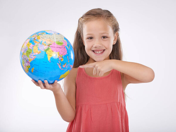 Lets give our children the world. A cute little girl holding a globe isolated on white