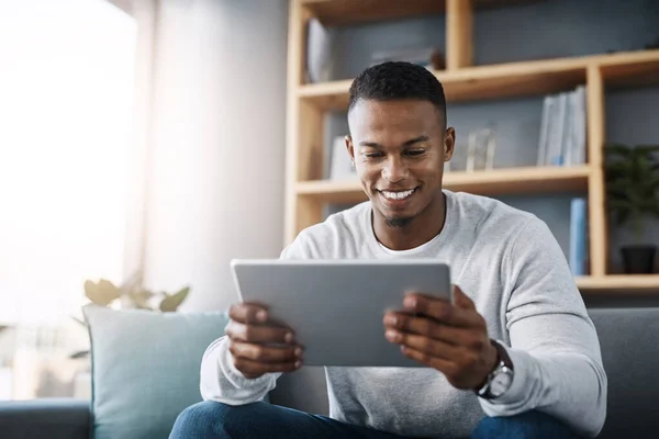 stock image Relax, tablet and happy man on sofa reading social media meme, email or streaming video on subscription service. Happiness, internet and connection, male with smile on face and movie website on couch.