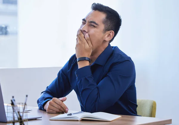 stock image I just want t go home to my bed...a young businessman yawning while working in an office