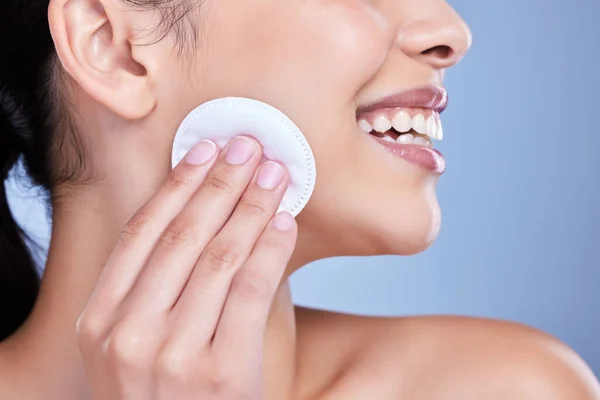 stock image A beautiful smiling mixed race woman using a cotton pad to remove makeup during a selfcare grooming routine. Hispanic woman applying cleanser to her face against blue copyspace background.