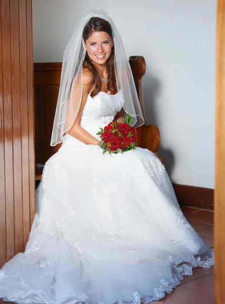 stock image Ready to get married. Portrait of a young bride sitting on a pew holding a bouquet of roses