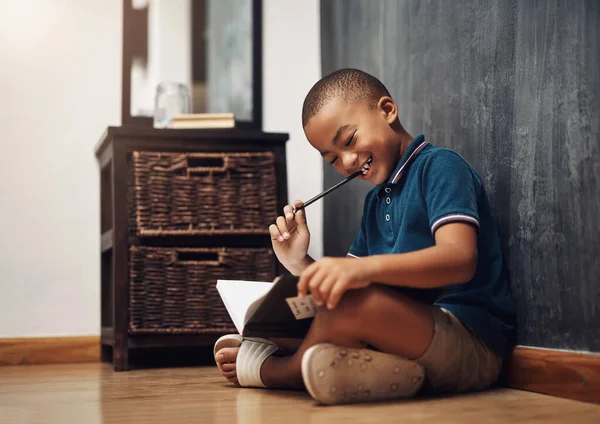 写作是一种神奇的媒介 坐在家里写书的小男孩 — 图库照片