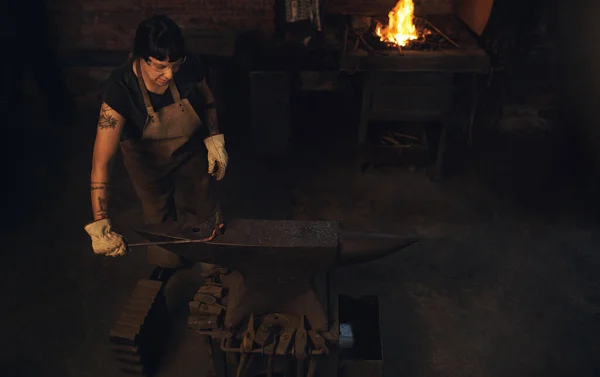 锻钢是她的堡垒 在铸造厂用铁锤击打热金属棒的年轻女子 — 图库照片