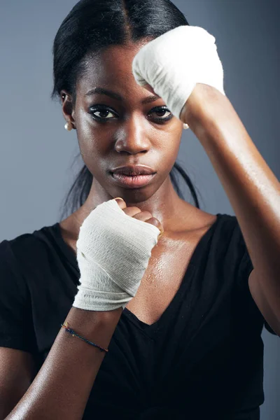 Portrait, fighting and a woman boxer in studio on a gray background for self defense, fitness or training. Health, exercise and workout with a black female fighter practising for a boxing competition.