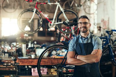 Portre, gülümseme ve tamirci dükkanında kollarını kavuşturup mağazada çalışıyor. Yüz, bisiklet tamircisi ve Kanada 'dan kendine güvenen, mutluluk, gözlük ve bisiklet atölyesinde olgun bir erkek.
