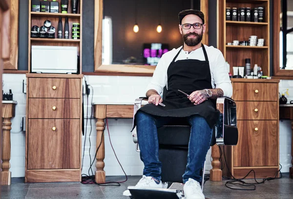 Cutting hair is my type of art. Full length shot of a handsome young barber sitting on a chair inside his barbershop