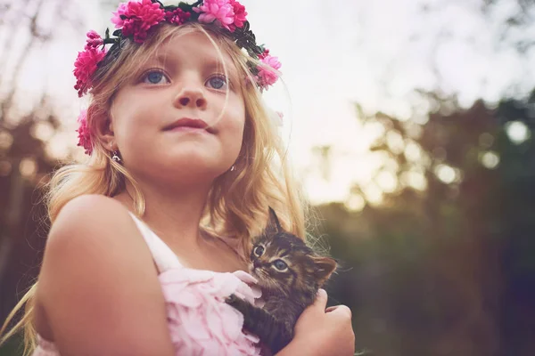I think theres room for one more at my party. a little girl holding a kitten and looking into the distance while standing outside in nature