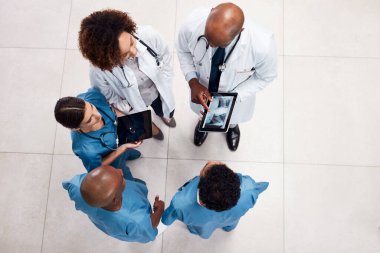 Seni daha iyi hissettirmek için her zaman bir planları vardır. Bir grup genç doktorun bir hastanenin içinde dijital tablet üzerinde tartışırken yüksek açılı görüntüsü.