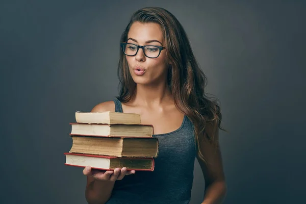 本のように興奮するものは何もない 灰色の背景に本の山を保持若い女性のスタジオショット — ストック写真