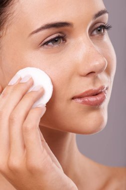 Skincare comes first. A young woman wiping her face with cotton wool