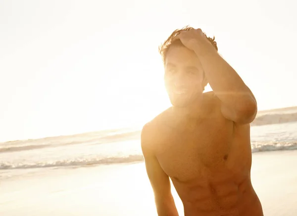 海のそばで日光浴 背後に太陽が沈むビーチに立つハンサムな男 — ストック写真