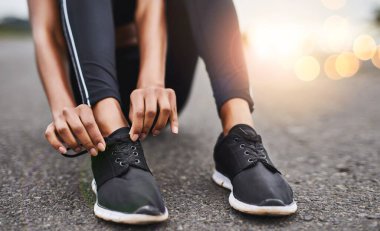 Yola koyulma vakti geldi. Spor ayakkabı bağcıklarını dışarıda egzersiz yaparken bağlayan bir kadının yakın plan fotoğrafı.