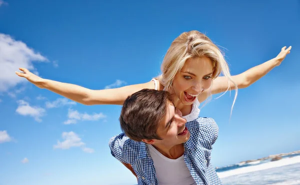 给你的夏天添些愚蠢的东西 一对快乐的年轻夫妇在海滩上享受着搭便车的乐趣 — 图库照片