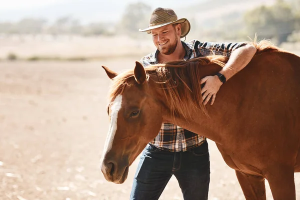Hes developed a special bond with horses. a farmer standing with a horse on a ranch