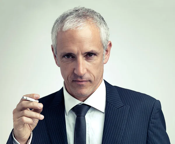 stock image Smoking suits him. A cropped portrait of a serious mature man in a pinstripe suit smoking a cigarette