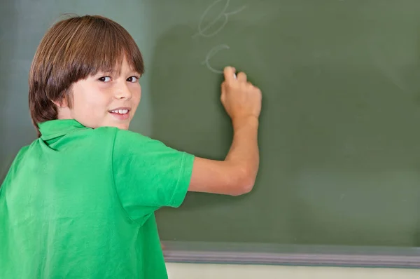 他知道答案 一个在学校黑板上写字的小男孩 — 图库照片