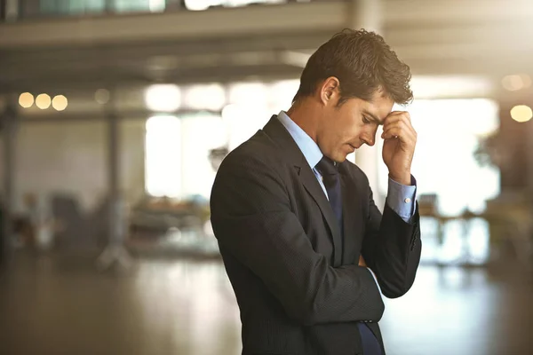 Headache, stress businessman standing and at his office sad or upset at debt fail at work. Mental health or anxiety, burnout and exhausted or depressed male corporate worker frustrated and tired.