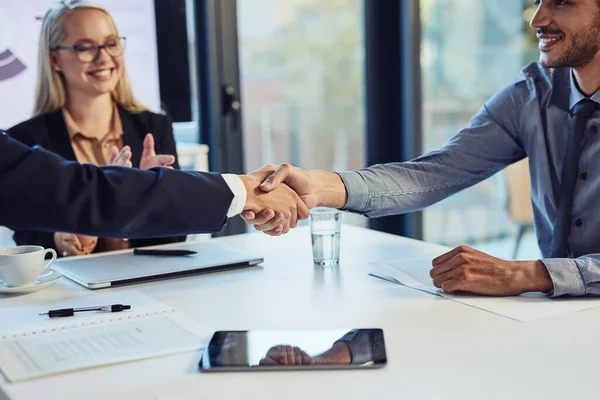 取引は彼らのビジネスをよくする 近代的なオフィスでの会議中に同僚と握手をする若いビジネスマンは — ストック写真