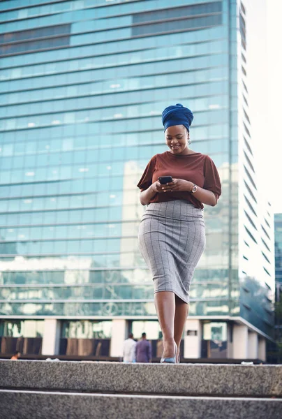 Black woman, phone text and city walking of a employee with happiness and social network app. African female person, mobile communication and networking with tech and internet by urban streets.