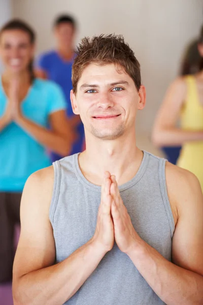 Finding his inner buddah. A young man smiling in yoga class with his classmates in the background