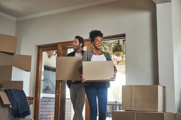Happy couple, real estate and boxes in new home for renovation, investment or relocation together. Interracial man and woman real estate owner carrying box in house, move or mortgage for property.