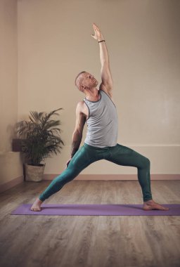 Yoga ruhu değiştirir. Yakışıklı bir delikanlının kapalı bir seans sırasında ayakta durup yoga pozu verirken uzun bir çekim.