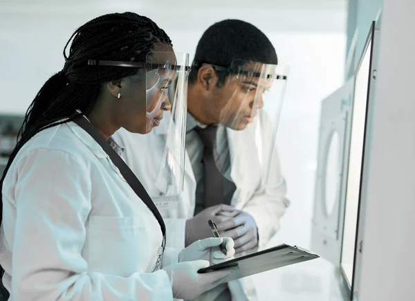 新しい発見を進める 2人の科学者は顔の盾を身につけながら研究室で — ストック写真