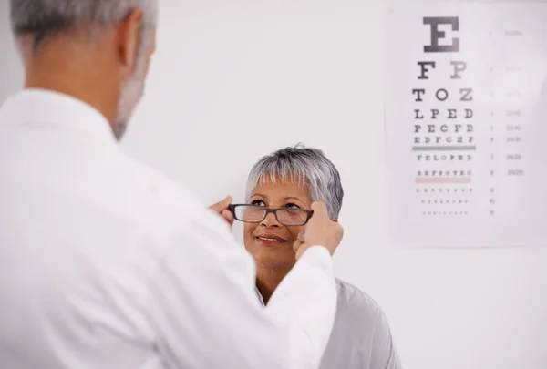 Optometrist doctor, elderly patient and glasses for vision, eye exam in medical consultation at optometry practice. Prescription lens, frame and senior man help woman in clinic with health insurance.