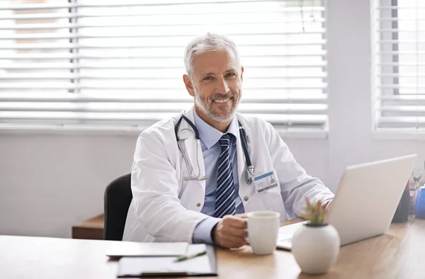 笔记本电脑和一个男医生的肖像在他的办公室在医院做诊断研究 在诊所配备计算机的自信 成功和职业成熟的男性保健工作者 — 图库照片