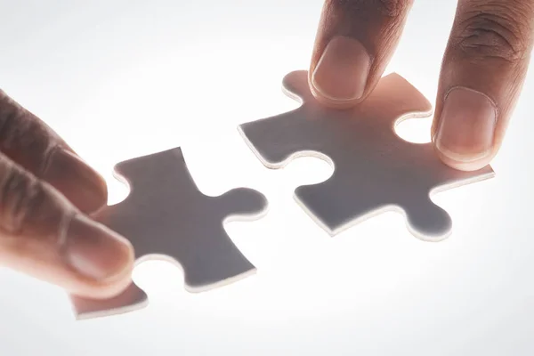 stock image Hands, puzzle and strategy in closeup for problem solving, mindset or connection with glow by white background. Games, jigsaw and link for innovation, synergy and solution with people, team or help.