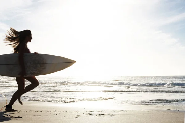 シルエット 女性サーファーはビーチの砂と海で走り 自然の中でサーフィンするためにサーフボードで屋外で運動します サーフィンやモックアップスペースのための海の波に実行されている女性とスポーツ 影と太陽 — ストック写真