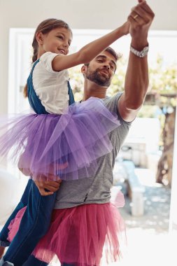Baba ve kızı balerin eteğiyle dans ediyor, evde sevgi ve ilgiyle eğleniyor aile, kız ve erkek oturma odasında dans ediyor, tasasız ve ilişki ve neşe içinde vakit geçiriyorlar..