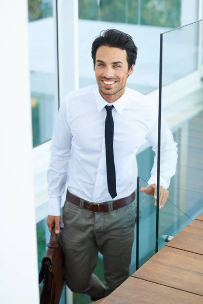 Happy, corporate and professional with a business man on stairs in a modern at work for progress. Smile, staircase and promotion with a handsome young male employee walking into his workplace.