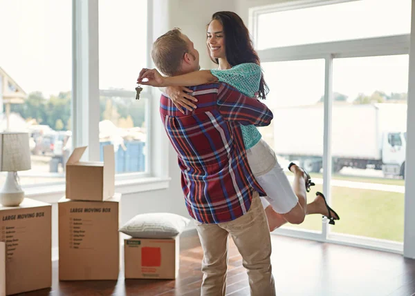 Happy couple, keys and moving into new home or hug for mortgage or property buy and boxes in empty lounge together. Real estate, man and woman excited for rent or embrace and house with open space.