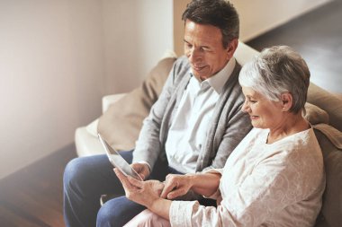 Tablet, rahatla ya da yaşlı çiftin evde birlikte film izlemesi ya da evde emeklilik aboneliği hakkında film izlemesi. Aşk, internet ya da yaşlı bir adamla oturma odasındaki kanepede video izleyen yaşlı bir kadın..