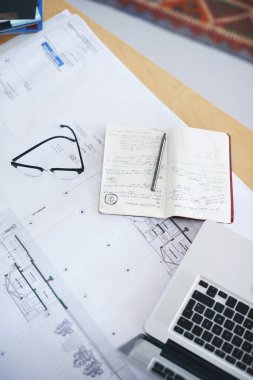 Not defteri, dizüstü bilgisayar ve planlar yukarıda, mimari planlama, strateji ya da ofis düzeni için. Çalışma alanı hakkındaki inşaat fikirleri için en iyi belge, kat planı veya mimarlık notları.