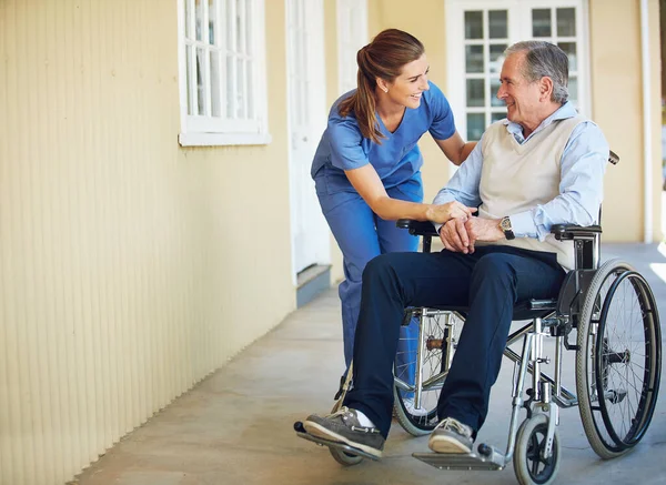 Konuşan, mutlu bir bakıcı ya da yaşlı bir hastaya klinikte yardım eden tekerlekli sandalyedeki yaşlı bir adam. Sağlık hemşiresi ya da sosyal hizmet görevlisi engelli yaşlılarla konuşuyor.