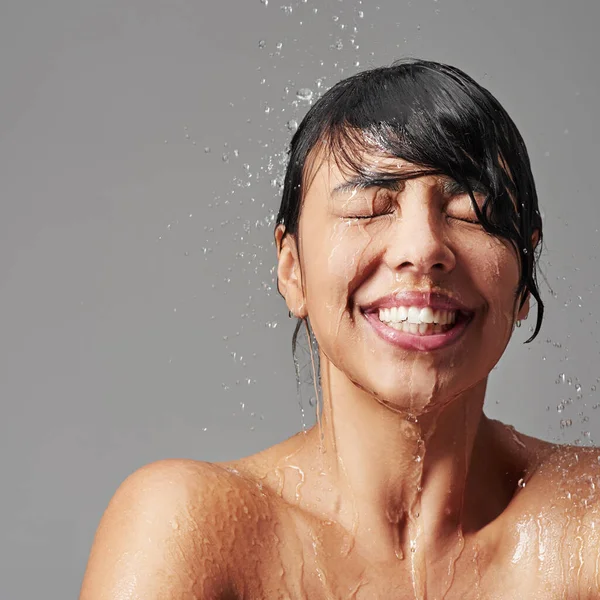シャワー 健康のためのスタジオで水スプラッシュを持つ女性のクリーニングと顔 美しさと身づくろい 髪を洗うためのスキンケア バスルームと幸せな女性の人 体と灰色の背景にクレンジング — ストック写真