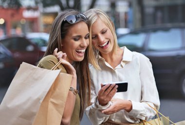 Alışveriş, telefon ve mutlu şehir arkadaşları Kara Cuma seçeneğine, pazar seçimine veya moda kıyafetleri için çevrimiçi perakende satış anlaşmasına bakıyorlar. Kentliler, internet aramaları ve İngiltere kadınları marka tanıtımına gülüyor.