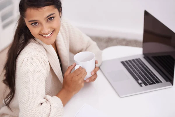 彼女のラップトップの前の自宅で 美しい民族の女性がノートパソコンの前でコーヒーを飲みながら座っている — ストック写真