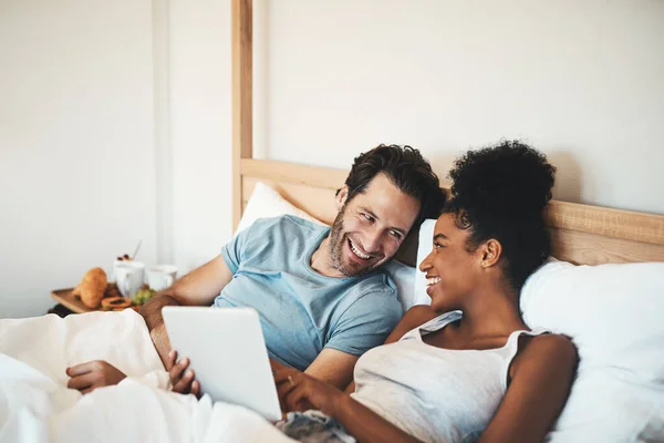 幸せなカップル タブレットや冗談 面白いエンターテイメントや自宅でオンラインストリーミングのためのベッドで笑っている 技術の異人種間の男と女の人は ベッドルームで朝やソーシャルメディアのためにリラックス — ストック写真