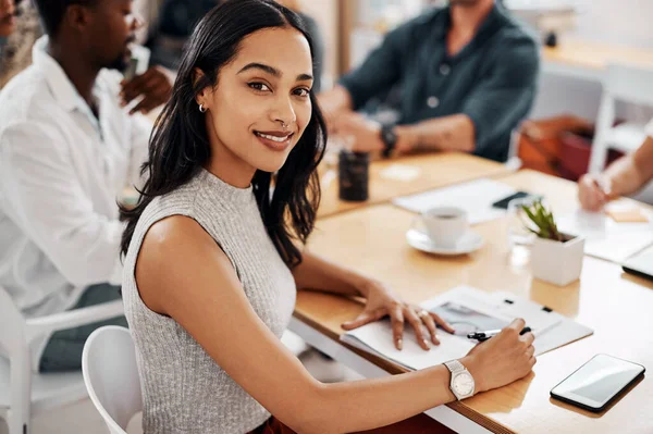 stock image Here to achieve success alongside my team. Portrait of a young businesswoman sitting in an office with her colleagues in the background