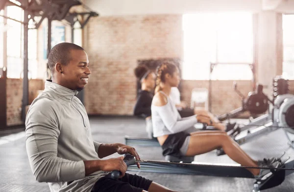 stock image An all round awesome exercise machine. a young man working out with a rowing machine in the gym