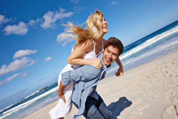 很高兴能去度假 一对快乐的年轻夫妇在海滩上享受着搭便车的乐趣 — 图库照片