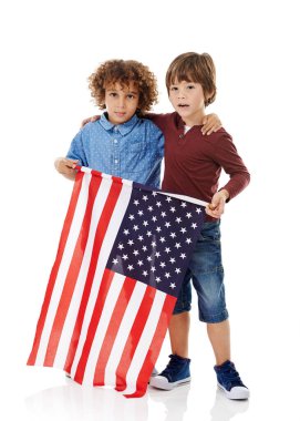 Vatansever dostlar. Beyaz bir arka planda Amerikan bayrağını bir arada tutan iki küçük çocuğun stüdyo fotoğrafı.