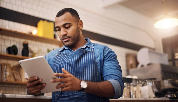 Focus, tablet and manager with man in cafe for online, entrepreneurship and startup. Waiter, technology and food industry with small business owner in restaurant for barista, african and coffee shop.